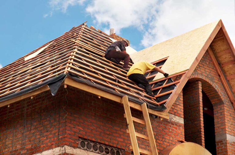 Homeowner inspecting dry attic insulation beneath a newly installed roof after rain.