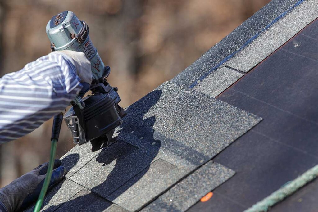 A residential roof eave with visible soffit, fascia, gutter, and downspout during light rain.