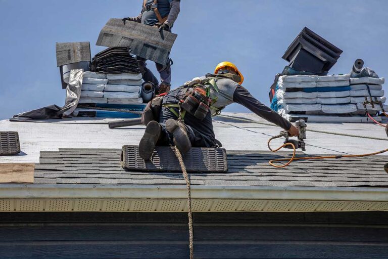 Homeowner examining worn shingles, metal flashing, and granules in a residential roof gutter