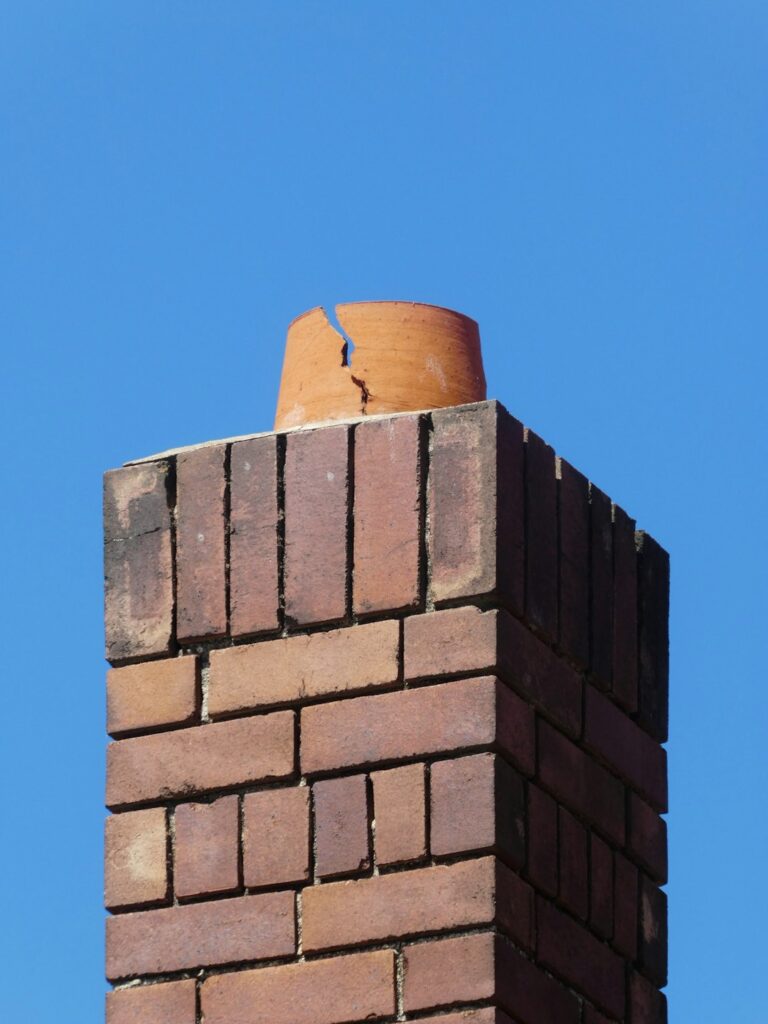 A homeowner examines a ceiling stain beneath a roof leak while water collects in a bucket.